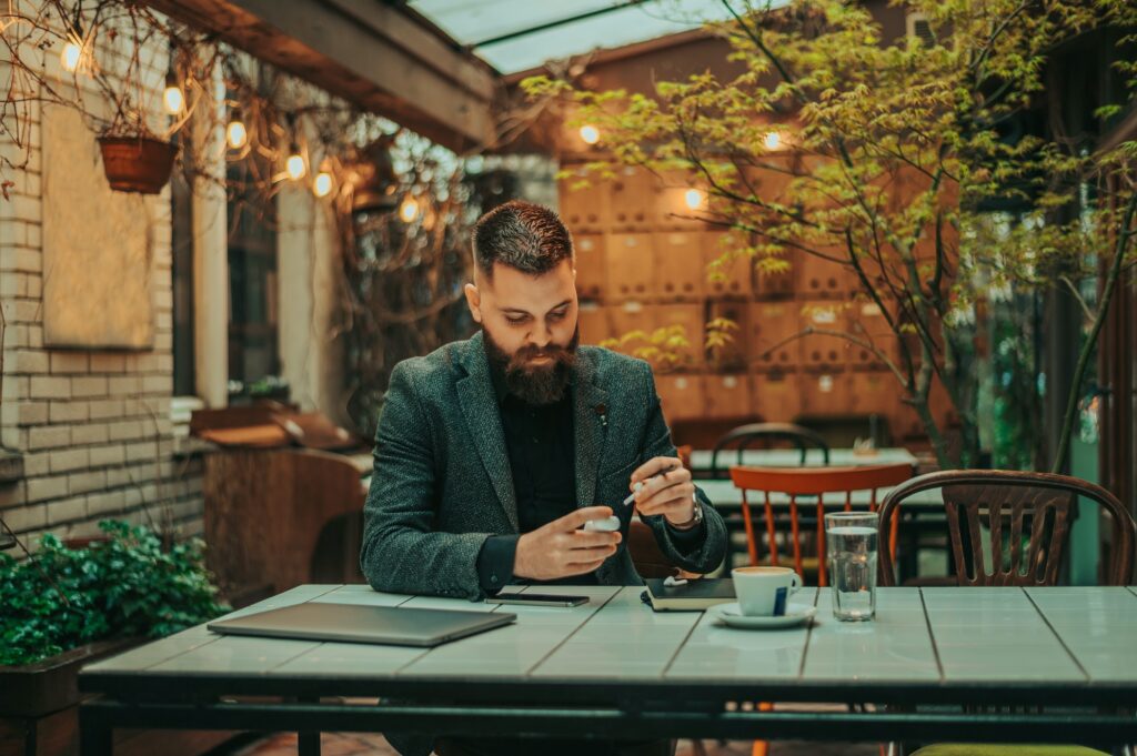 Businessman using airpods and a laptop in a coffee shop